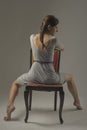 Beautiful caucasian girl slouching on chair - gray background with copy space