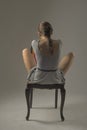 Beautiful caucasian girl slouching on chair - gray background with copy space