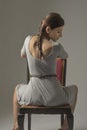 Beautiful caucasian girl slouching on chair - gray background with copy space