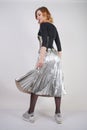 Beautiful caucasian girl wearing futuristic pvc corset and plaid metallic skirt with mirrored running shoes on white background in