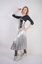 Beautiful caucasian girl wearing futuristic pvc corset and plaid metallic skirt with mirrored running shoes on white background in