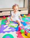 Beautiful caucasian infant playing with toys at colorful playroom