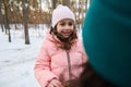 Beautiful Caucasian little girl in a warm pink down jacket taking a cookie out of a lunch box, enjoying a break for lunch with her Royalty Free Stock Photo