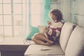 Beautiful caucasian middle age woman with curly hair working at home and relaxing on the sofa with a tablet and internet. drinking