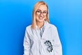 Beautiful caucasian oculist woman wearing robe and optometry glasses looking positive and happy standing and smiling with a Royalty Free Stock Photo