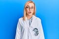 Beautiful caucasian oculist woman wearing robe and optometry glasses scared and amazed with open mouth for surprise, disbelief