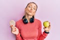 Beautiful caucasian sports woman holding green apple and rice crackers looking at the camera blowing a kiss being lovely and sexy Royalty Free Stock Photo