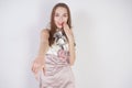 Beautiful caucasian teen girl stands in a short evening dress and mocks the interlocutor, humiliating, on a white background in th