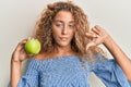 Beautiful caucasian teenager girl holding green apple with angry face, negative sign showing dislike with thumbs down, rejection Royalty Free Stock Photo