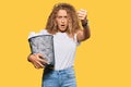 Beautiful caucasian teenager girl holding paper bin full of crumpled papers annoyed and frustrated shouting with anger, yelling