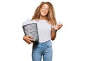 Beautiful caucasian teenager girl holding paper bin full of crumpled papers looking positive and happy standing and smiling with a