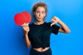 Beautiful caucasian teenager girl holding red ping pong rackets with angry face, negative sign showing dislike with thumbs down,