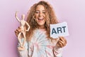 Beautiful caucasian teenager girl holding wooden manikin and art word smiling and laughing hard out loud because funny crazy joke Royalty Free Stock Photo