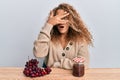 Beautiful caucasian teenager girl making grape jam peeking in shock covering face and eyes with hand, looking through fingers