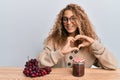 Beautiful caucasian teenager girl making grape jam smiling in love doing heart symbol shape with hands Royalty Free Stock Photo