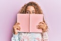 Beautiful caucasian teenager girl reading a book covering face smiling with a happy and cool smile on face Royalty Free Stock Photo