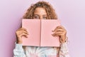 Beautiful caucasian teenager girl reading a book covering face smiling and laughing hard out loud because funny crazy joke Royalty Free Stock Photo