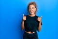 Beautiful caucasian teenager girl wearing black sportswear success sign doing positive gesture with hand, thumbs up smiling and Royalty Free Stock Photo