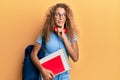 Beautiful caucasian teenager girl wearing student backpack and holding books serious face thinking about question with hand on Royalty Free Stock Photo