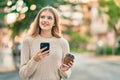 Beautiful caucasian teenager using smartphone and drinking coffee at the city Royalty Free Stock Photo