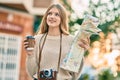 Beautiful caucasian tourist teenager drinking coffee holding map at the city