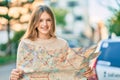 Beautiful caucasian tourist teenager smiling happy holding map at the city