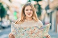 Beautiful caucasian tourist teenager smiling happy holding map at the city