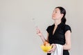 Beautiful Caucasian woman with black shirt holding an eggbeater and a yellow bowl full of chicken eggs