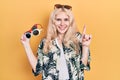 Beautiful caucasian woman with blond hair holding many sunglasses smiling with an idea or question pointing finger with happy Royalty Free Stock Photo