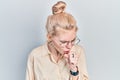 Beautiful caucasian woman with blond hair wearing casual look and glasses feeling unwell and coughing as symptom for cold or Royalty Free Stock Photo