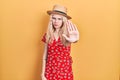 Beautiful caucasian woman with blond hair wearing summer hat doing stop sing with palm of the hand Royalty Free Stock Photo