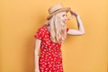 Beautiful caucasian woman with blond hair wearing summer hat very happy and smiling looking far away with hand over head Royalty Free Stock Photo