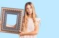 Beautiful caucasian woman with blonde hair holding empty frame thinking attitude and sober expression looking self confident Royalty Free Stock Photo