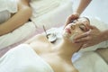 Beautiful caucasian woman cleaning makeup before massage and making facial mask treatment on face in Spa salon