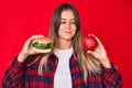Beautiful caucasian woman comparing burger and healthy red apple smiling looking to the side and staring away thinking Royalty Free Stock Photo