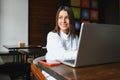 Beautiful Caucasian woman dreaming about something while sitting with portable net-book in modern cafe bar, young charming female Royalty Free Stock Photo