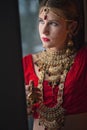 Beautiful caucasian woman dressed in Indian bridal Sari along with specific jewelry: Mangalsutra, Thaali, Maang Tikka, Choora, Nat