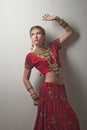 Beautiful caucasian woman dressed in Indian bridal Sari along with specific jewelry: Mangalsutra, Thaali, Maang Tikka, Choora, Nat