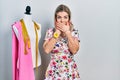 Beautiful caucasian woman dressmaker designer by manikin shocked covering mouth with hands for mistake Royalty Free Stock Photo