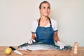 Beautiful caucasian woman fishmonger selling fresh raw salmon smiling looking to the side and staring away thinking