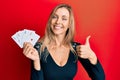 Beautiful caucasian woman holding ace poker cards smiling happy and positive, thumb up doing excellent and approval sign