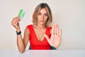 Beautiful caucasian woman holding birth control pills with open hand doing stop sign with serious and confident expression, Royalty Free Stock Photo