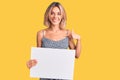 Beautiful caucasian woman holding blank empty banner pointing finger to one self smiling happy and proud Royalty Free Stock Photo