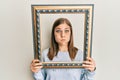 Beautiful caucasian woman holding empty frame puffing cheeks with funny face Royalty Free Stock Photo