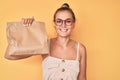 Beautiful caucasian woman holding take away paper bag looking positive and happy standing and smiling with a confident smile Royalty Free Stock Photo