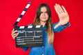 Beautiful caucasian woman holding video film clapboard with open hand doing stop sign with serious and confident expression,