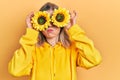 Beautiful caucasian woman holding yellow sunflowers over eyes puffing cheeks with funny face Royalty Free Stock Photo