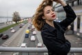 Beautiful Caucasian woman leaning on a bridge over the highway In Winter Time. Royalty Free Stock Photo