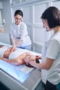 Beautiful Caucasian woman lying on massage table while receiving hand massage on face and body in spa selon