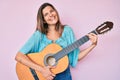 Beautiful caucasian woman playing classical guitar smiling and laughing hard out loud because funny crazy joke